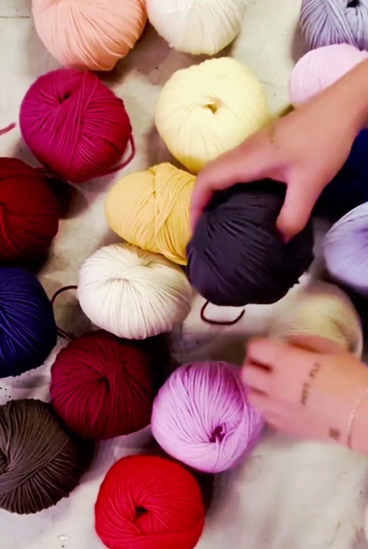 Gomitoli di cotone e lana di tanti colori sul tavolo